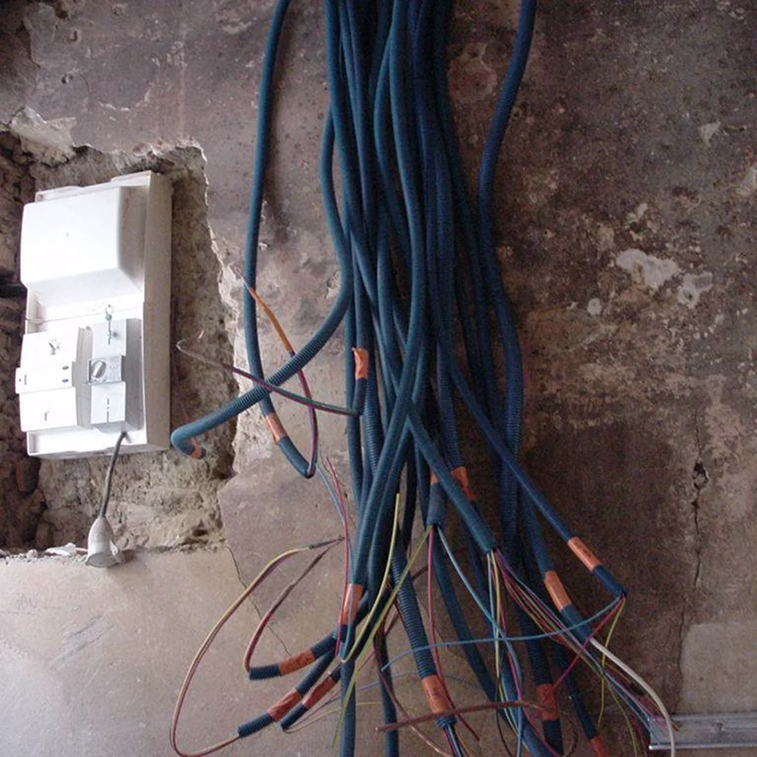 Passage de gaines électriques dans un mur de pierre en rénovation